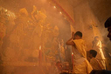 KOLKATA, INDIA - 27 EPTEMBER 2017: Durga Puja festivali ayini, kutsal duman altında Tanrıça Durga 'ya dua eden genç Hindu rahip. - Renkli ışığın altında gece çekilmiş. Hinduizm Festivali.