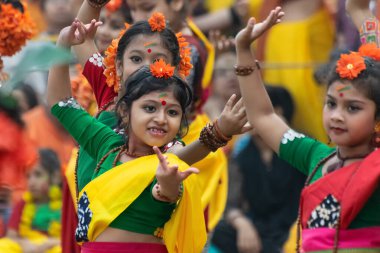 KOLKATA, INDIA - 1 Mart 2018: Sarı ve yeşil sari giymiş genç kız dansçılar - Palash çiçekli geleneksel Hint elbisesi, Butea monosperma, Holi Bahar Festivali 'nde dans .