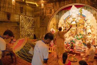 KOLKATA, INDIA - SEPTEMBER 27, 2017: Hindu Rahiplerin tanrıça Durga 'ya tapmaları, onun arka tarafında dhaakis (davulcular) performansı. Durga Puja festivali ritüeli - adı Durga aarti. renkli ışık.