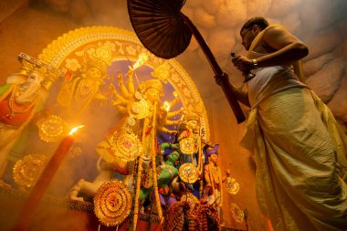 Kolkata, Hindistan - 16 Ekim 2018: Durga Puja festivali ritüeli altında tanrıça Durga 'ya tapan genç Hindu rahip. -... renkli ışık ve kutsal dumanın altında çekiliyor. Durga Puja Festivali.