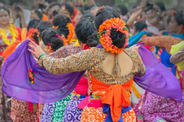Kolkata, Hindistan - 1 Mart 2018: Renkli sari (geleneksel Hint elbisesi) ve Palash çiçekleri (Butea monosperma) giymiş kız dansçılar, Dol (Bengalce) veya Holi (Hintçe) festivalinde dans ediyorlar..