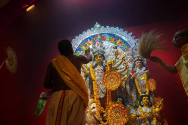 Kolkata, Hindistan - 16 Ekim 2018: Hindu rahibi pandalın içinde Tanrıça Durga 'ya tapıyor, geçici tapınak, Durga Puja festivali ritüeli - gece vakti renkli ışık altında çekiliyor. Hinduizm Festivali.