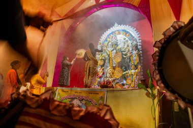Kolkata, Hindistan - 16 Ekim 2018: Hindu rahip dumanın altında Dhaakis -davulcularla- Tanrıça Durga 'ya tapıyor. Durga Puja - gece çekilen renkli ışık altında .