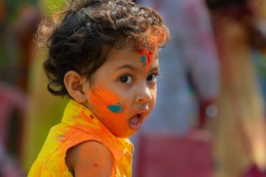 Kolkata, Hindistan - 21 Mart 2019: Yüzünde bahar festivali renginde güzel bir çocuk, Holi festivalinde Dol (Bengalce) ya da Holi (Hintçe) olarak bilinen ifadesini esnetiyor.).