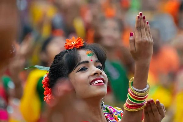 KOLKATA , INDIA - MARCH 1, 2018: Expression of girl dancer, dressed in traditional Indian sari and Palash flowers - Butea monosperma, make up, dancing at Dol or Holi - the spring festival in India.