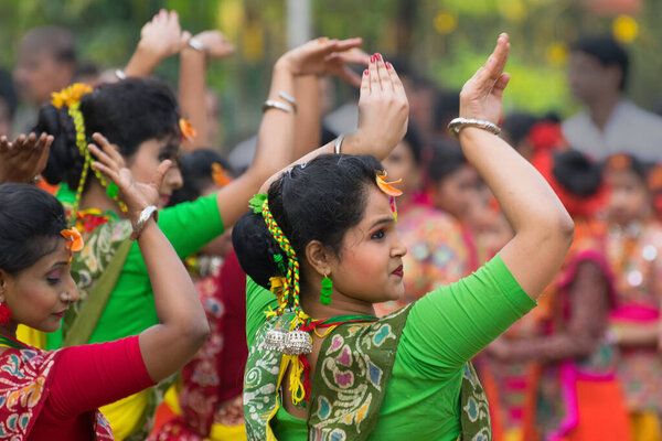 KOLKATA , INDIA - MARCH 12, 2017: Dancing pose of girl dancer, dressed in yellow and red coloured sari (traditional Indian dress) and flowers dancing at dol / holi festival.