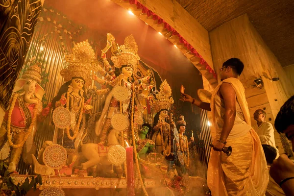 KOLKATA , INDIA - SEPTEMBER 27, 2017 : Young Hindu Priest worshipping Goddess Durga under holy smoke, Durga Puja festival ritual. - shot at night under colored light. Festival of Hinduism.
