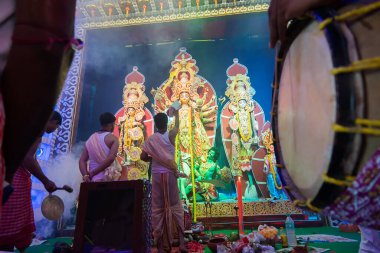 Howrah, Batı Bengal, Hindistan - 5 Ekim 2019: Geleneksel dhaaks çalınırken, Hindu Bengalli rahip Durga 'ya sari, Durga aarti' nin kutsal dumanı altında gece çekimleri sırasında ibadet ediyor..