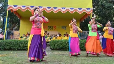 Kolkata, Batı Bengal, Hindistan - 10 Mart 2020: Renkli Hint elbiseleri giymiş genç Bengalli kızlar, Dol utsab veya Holi festivalinde dans ediyorlar. Hindistan 'a baharın gelişini kutluyoruz. 4K görüntü.