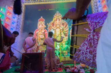 Howrah, Batı Bengal, Hindistan - 5 Ekim 2019: Geleneksel dhaakiler dhaaks oynarken Hindu Bengalli rahipler Durga, Durga aarti 'ye gece çekimleri sırasında kutsal duman altında tapıyorlar..