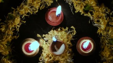 Rangoli çiçeklerinin üst görüntüsü ve dört mum ya da diyas, geceleri Diwali ışıkları. Koyu arkaplan Stok görüntüleri.