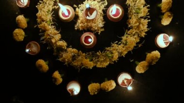 Rangoli çiçeklerinin üst görüntüsü çemberin içine konur ve etraflarına mumlar ya da diyalar yerleştirilir, geceleri Deepawali ışıkları. Karanlık arkaplan görüntüsü.