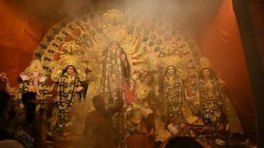 Kolkata, Batı Bengal, Hindistan - 7 Ekim 2019: Hindu Purohit tanrıça Durga 'ya tapıyor elinde panchapradip, geleneksel Hindu ritüeli Durga Puja - renkli ışık ve kutsal duman altında vuruldu.