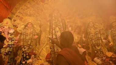 Kolkata, Batı Bengal, Hindistan - 7 Ekim 2019: Hindu Purohit Tanrıça Durga 'ya tapıyor elinde pradip, geleneksel Hindu ritüeli Durga Puja - renkli ışık ve ağır kutsal dumanın altında vuruldu.