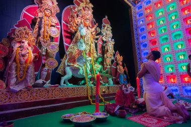 Howrah, Batı Bengal, Hindistan - 5 Ekim 2019: Hindu Bengali purohit Durga Puja pandalı içinde Tanrıça Durga 'ya saygı ve paraşütle eğiliyor. Ünlü Durga Puja Hinduizm Festivali.