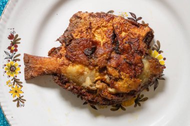 Kızarmış pomfret balığı beyaz bir tabakta servis edilir, baharatlı Hint yemeği. Pomfretler Bramidae familyasına ait balık türleridir..