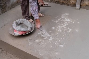 Hindistan işçiliği, düz mala kullanarak zemini düzleştiriyor ve elle beton dağıtıyor. Stok görüntüsü..