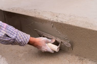 Düz mala ve çimento kullanarak zeminin alçılı yan duvarını elle döşeyen Hint işçiliği. Stok resmi..