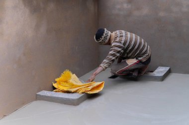 Howrah, Batı Bengal, Hindistan - 6 Ocak 2020: Hindistan işçi sınıfı, düz mala ve beton kullanarak alçılı zemini elle düzleştiriyor. Resim yükle.