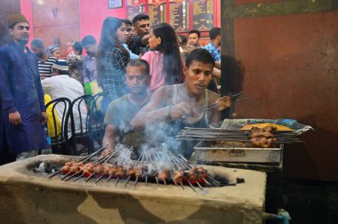 KOLKATA, Batı BENGAL, INDIA - 27 Mayıs 2019: Tavuk-avlama kebapları akşam saatlerinde Hindistan 'ın Kolkata kentinde sokak yemeği olarak satılmak üzere metal şişler ile ızgarada kızartılıyor.