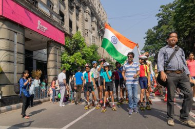 KOLKATA, Batı BENGAL, INDIA - 21 Mart 2015: Hindistan ulusal bayrağıyla Park Street 'te çocuklar paten kayıyor ve tezahürat yapıyor. Sabah güneşinin altında bir gurur anı.