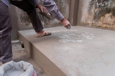 Hindistan işçiliği, düz mala kullanarak zemini düzleştiriyor ve elle beton dağıtıyor. Stok görüntüsü..