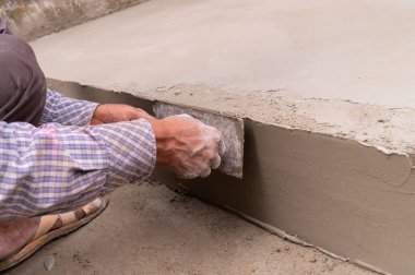 Düz mala ve çimento kullanarak zeminin alçılı yan duvarını elle döşeyen Hint işçiliği. Stok resmi..