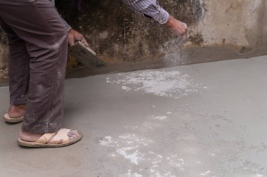Hindistan işçiliği, düz mala kullanarak zemini düzleştiriyor ve elle beton dağıtıyor. Stok görüntüsü..