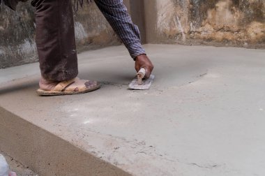 Hintli işçilerin alçılı zemini düz mala ve beton kullanarak elle düzleştirmesi, stok imajı.