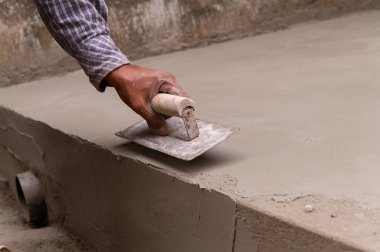 Hintli işçilerin alçılı zemini düz mala ve beton kullanarak elle düzleştirmesi, stok imajı.