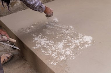 Hindistan işçiliği, düz mala kullanarak zemini düzleştiriyor ve elle beton dağıtıyor. Stok görüntüsü..