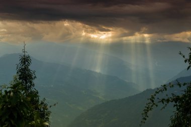 Rabangla, Sikkim, Hindistan 'dan gelen güneş ışınları. Ön planda Slihoutte ağaçları ve arka planda Himalaya dağları. Sikkim 'li Büyük Himalayalar' ın muhteşem manzarası..