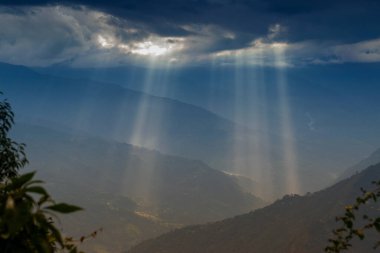 Rabangla, Sikkim, Hindistan 'dan gelen güneş ışınları. Ön planda Slihoutte ağaçları ve arka planda Himalaya dağları. Sikkim 'li Büyük Himalayalar' ın muhteşem manzarası..