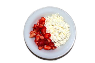 Lezzetli süzme peynirli bir tabak ve beyaz üzerine izole edilmiş kırmızı çilek.
