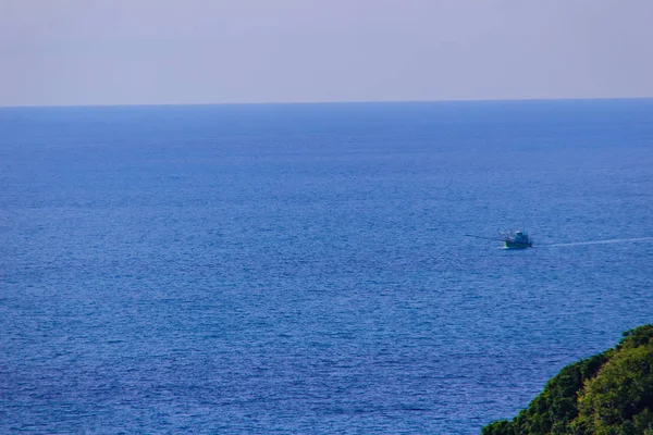 Colorful marine landscape with fisherman boat against deep blue sea under blue sky in the ocean on the cloudy day at Phuket, Thailand.