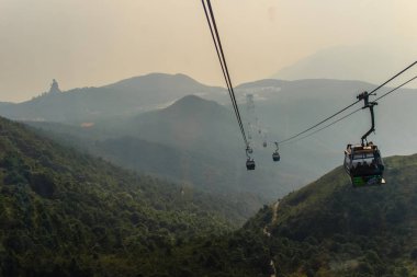Tele yakınlaştırma görünümü Ngong Ping 360 kablo araba Po Lin manastırda Lantau Island, Hong Kong, dağ tepe üzerinde dev Tian Tan Buddha heykeli göster