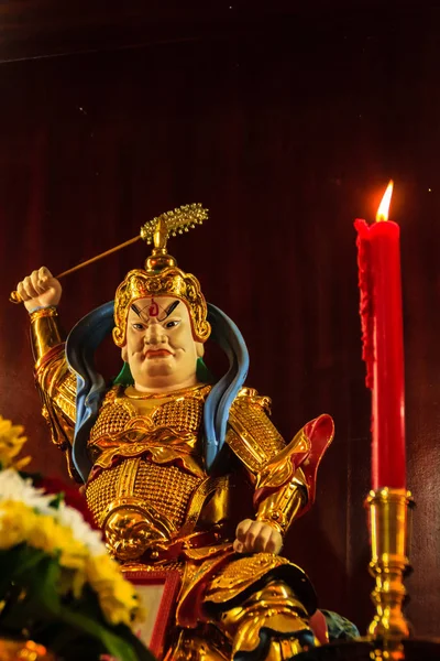 Red candle and colorful statue of Cai Shen, Chinese God of wealth, God of fortune, which is a symbol for bringing good luck. Cai Shen, the Chinese god of Prosperity, a popular Chinese New Year symbol