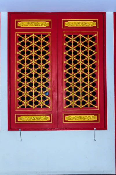 Beautiful Chinese style wooden red doors and windows with dragon Stencil art on Chinese Buddhist temple Thailand