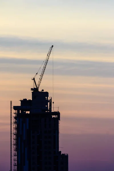 Beautiful silhouette of construction tower cranes with sunset sky background. Silhouette of the building construction with the tower cranes on top under the dramatic sky background.