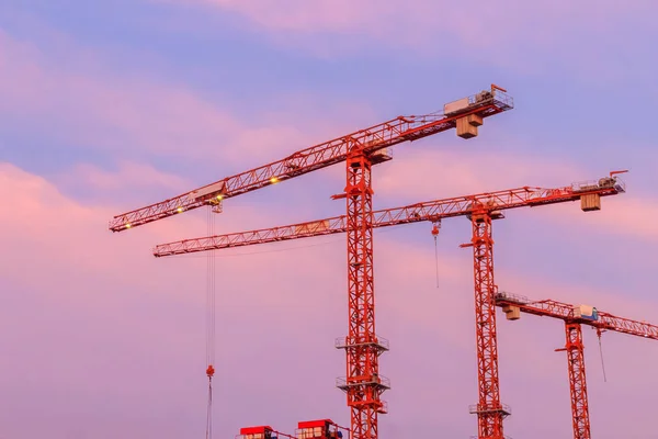 Beautiful silhouette of construction tower cranes with sunset sky background. Silhouette of the building construction with the tower cranes on top under the dramatic sky background.