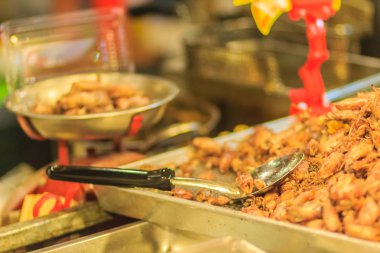 Satıcı, Bangkok, Tayland gece pazarında sarımsaklı kızarmış bebek kalamar satmaktadır.