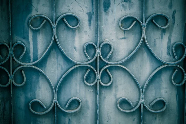 Old wrought iron bars on the gate with grunge and rusty steel  background. Iron Grill Ornamental Flourish Detail Background. The old rusty fence with metallic gate pattern, curved steel background.