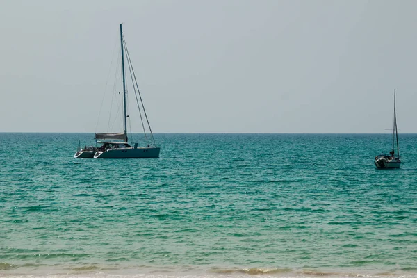 Salma tekne palamarla sahil tarafında, orman plaj görünümden. Orman ağaç ve Yelkenli deniz manzarası görünümü. Yat ve ağaç ile huzurlu plaj. Yelkenli veya salma tekne Naiyang Beach Phuket ağaç çerçevesindeki