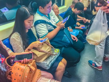 Bangkok, Tayland - 22 Şubat 2017: Bts (Bangkok kitle toplu taşıma sistemi), Bangkok, Tayland için toplu taşıma içinde akıllı telefon kullanan yolcular.