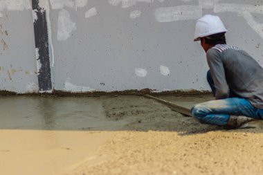 Duvar işçisi pürüzsüz veya seviyelendirme Beton zeminin iş adım bina inşaat için uzun mala kullanıyor.