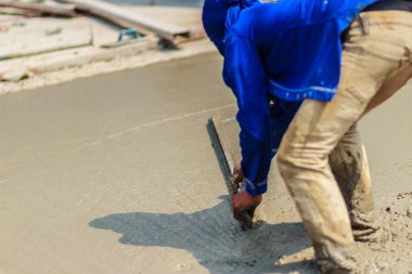 Duvar işçisi pürüzsüz veya seviyelendirme Beton zeminin iş adım bina inşaat için uzun mala kullanıyor.