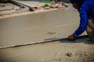 Duvar işçisi pürüzsüz veya seviyelendirme Beton zeminin iş adım bina inşaat için uzun mala kullanıyor.
