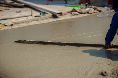 Duvar işçisi pürüzsüz veya seviyelendirme Beton zeminin iş adım bina inşaat için uzun mala kullanıyor.