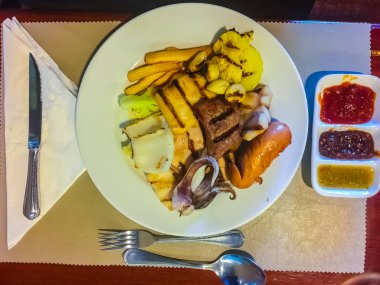 Sosis, sığır eti, kalamar, balık, sarımsak da dahil olmak üzere açık büfe dükkanda servis ızgara biftek ayarla, ananas, soslar çanak üzerinde.