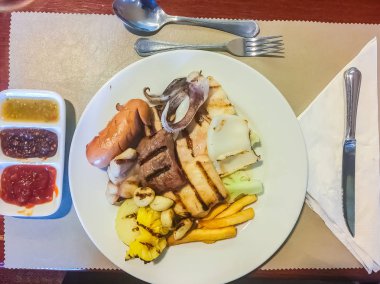 Sosis, sığır eti, kalamar, balık, sarımsak da dahil olmak üzere açık büfe dükkanda servis ızgara biftek ayarla, ananas, soslar çanak üzerinde.